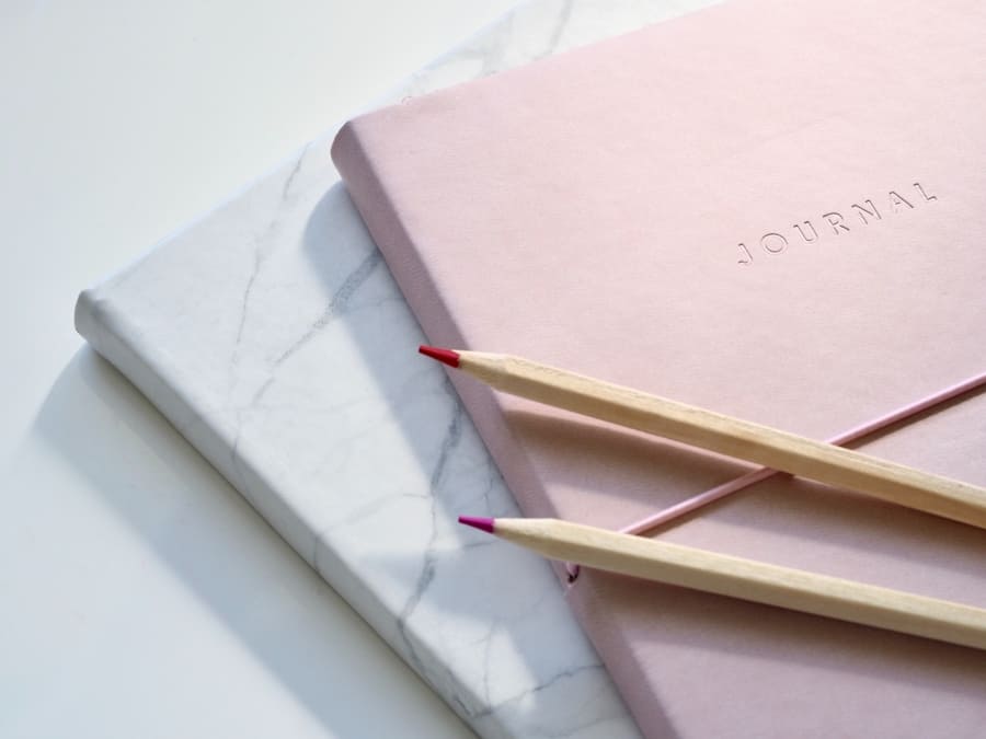 a pink journal and pencils